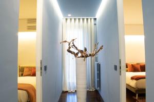 una habitación con 2 camas y un jarrón con una rama en Viale dei Lecci - Luxury rooms, en Francavilla Fontana