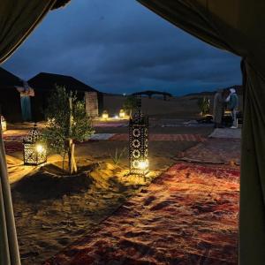 une tente éclairée dans le désert la nuit dans l'établissement Travel Oasis Merzouga Camp, à Merzouga