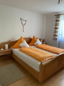 um quarto com 2 camas com almofadas laranja e branca em Ferienwohnung Grüntenblick em Rettenberg