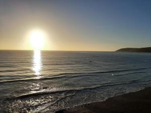 a sun setting over the ocean with a beach at Dunedin Guest House in Penzance