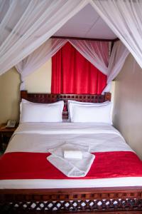 a bed with a red curtain and a red blanket at Turbine Ngong Hotel in Ngong