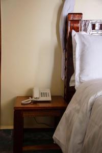 a telephone on a table next to a bed at Turbine Ngong Hotel in Ngong