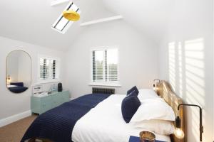 ein weißes Schlafzimmer mit einem Bett mit blauen und weißen Kissen in der Unterkunft The Jolly Sportsman in Lewes