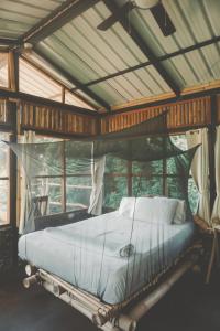 a bedroom with a canopy bed in a room with windows at La Bambouseraie in Balgue