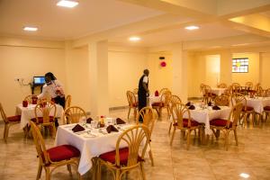 two people standing in a room with tables and chairs at Turbine Ngong Hotel in Ngong