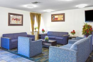 a waiting room with blue couches and a flat screen tv at OYO Hotel Irving DFW Airport South in Irving
