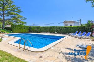 una piscina in un cortile con sedie a sdraio e una piscina di Villa Angels a El Vendrell