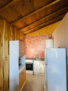 a kitchen with a white refrigerator and a brick wall at Ruka Huilipan in Nueva Imperial +11 photos