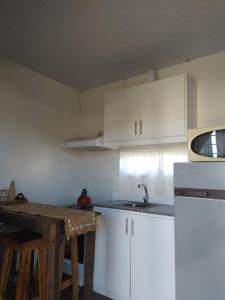 - une cuisine avec des placards blancs, un évier et une table dans l'établissement RenaPau, à La Paloma