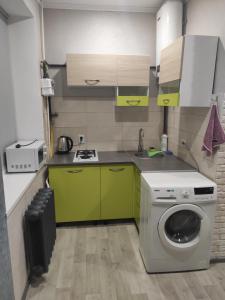 a kitchen with green cabinets and a washing machine at New apartments Уютная студия в центре города Дзержинка in Kryvyi Rih