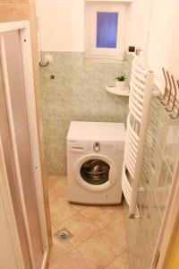 - un lave-linge dans une petite salle de bains avec fenêtre dans l'établissement Relax Wellness Apartman, à Parádsasvár