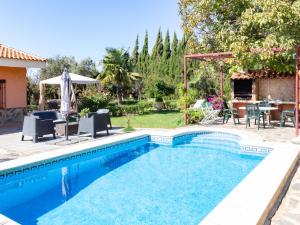 a swimming pool in a yard with chairs and a table at Cortijo rincón del sur in Nigüelas