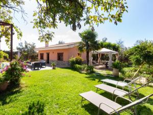 a garden with white benches in front of a house at Cortijo rincón del sur in Nigüelas