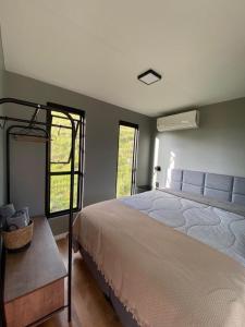 um quarto com uma cama grande e 2 janelas em Leão da Montanha - Hospedaria Rural em Cambará