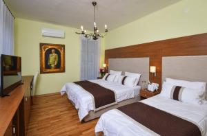 a hotel room with two beds and a flat screen tv at Penzion Zaka in Bled