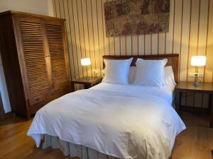 a bedroom with a large white bed with two lamps at Rectoral de Cines in Oza dos Ríos