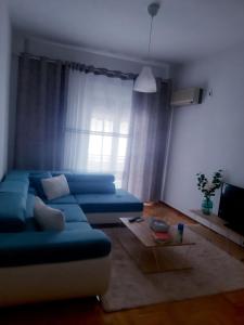 Maklen في أثينا: غرفة معيشة مع أريكة زرقاء أمام نافذة