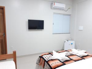 um quarto com uma cama e uma televisão na parede em Hotel Brio em Salinópolis
