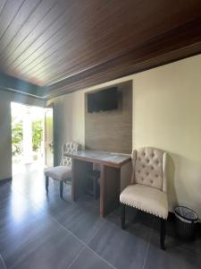 a room with a desk and two chairs and a television at Campos Arenal Hotel in Fortuna