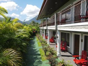 a walkway next to a building with red chairs at Campos Arenal Hotel in Fortuna
