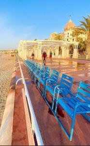 a row of blue chairs sitting on the beach at Carré d'or Very nice appart Near the beach in Nice