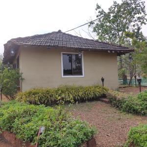 a small house with a window and some plants at Raigad Agro Park in Mahād