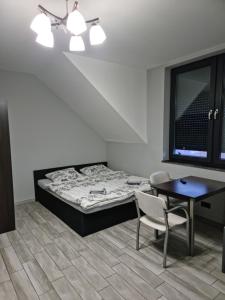 um quarto com uma cama, uma mesa e uma cadeira em Noclegi 24/h Leszczynek em Kutno