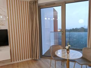 een kamer met een glazen tafel en stoelen en een groot raam bij Premium Apartament PINEA Pobierowo in Pobierowo