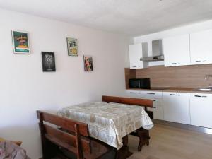 eine Küche mit einem Tisch und weißen Schränken in der Unterkunft Appartamento Magic Cervinia CIR VDA-VALTOURNENCHE n 0270 in Breuil-Cervinia