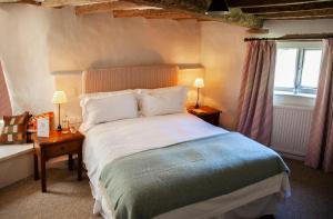 Un dormitorio con una cama grande y una ventana en The Lamb Inn, en Shipton under Wychwood