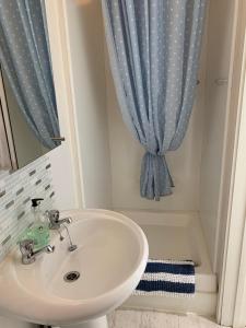 een badkamer met een wastafel en een blauw douchegordijn bij Little Karenza is the perfect Cornish getaway in Saint Anthony