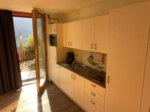 a kitchen with white cabinets and a large window at Brentwaldhof Appartements in Cornedo all'Isarco