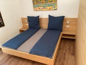 un letto con cuscini blu in una stanza di Brentwaldhof Appartements a Cornedo all'Isarco