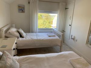 a bedroom with two beds and a window at Little Karenza is the perfect Cornish getaway in Saint Anthony