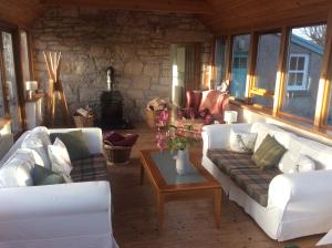 a living room with two white couches and a table at Auchencairn Cottage in Brora