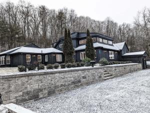 uma grande casa preta com uma parede de pedra em Hideaway Lodge - Glen Lake, Lake George em Lake George