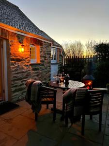 eine Terrasse mit einem Tisch und Stühlen sowie ein Haus in der Unterkunft The Old Dairy Retreat in St Austell