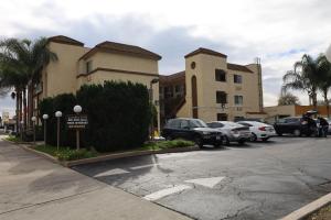 a parking lot with cars parked in front of buildings at Lambert Inn in Whittier