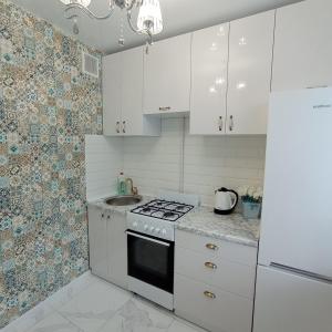 a kitchen with white cabinets and a stove and a sink at VIP Апартаменты СВЕТ ЕСТЬ ВСЕГДА!!! in Dnipro