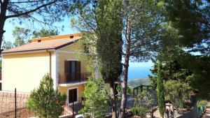 a yellow house with a fence and trees at Le Pigne casa vacanze. in Pollica
