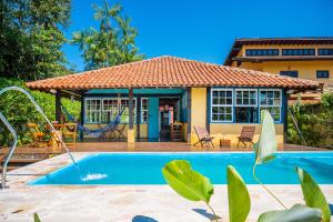 a house with a swimming pool in front of it at Casa do Pescador Camburi in Camburi