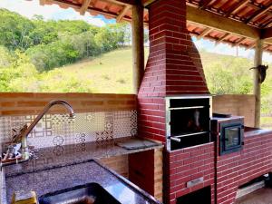an outdoor kitchen with a brick oven and a sink at sitio santa Eulalia in Cunha