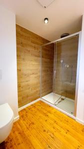 een badkamer met een douche, een toilet en houten vloeren bij Uraha Apartments Fürth in Fürth