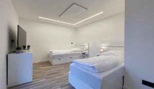 a white bedroom with two beds and a mirror at Uraha Apartments Fürth in Fürth