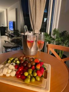 Apartamento Vida Boa في غرافاتال: صينية من الفاكهة وكأسين من النبيذ على الطاولة