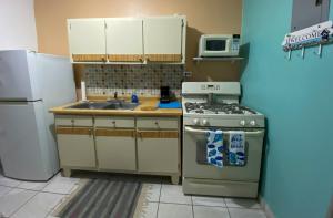 a kitchen with a stove and a sink and a refrigerator at Pirata Family House• A 5 min de Poblado Boquerón in Cabo Rojo