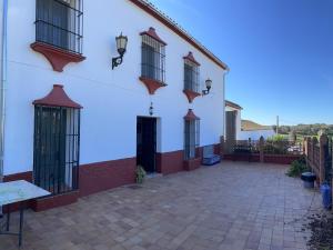 - un bâtiment blanc avec des fenêtres et une terrasse dans l'établissement Casa Rural Finca de las Encarnaciones Bajas, à Villanueva de San Juan