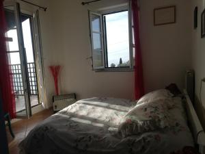 ein Schlafzimmer mit einem Bett und zwei Fenstern in der Unterkunft Ca' Clémentine in Sasso di Bordighera