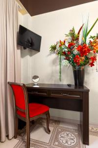 un escritorio con una silla roja y un jarrón de flores en Ashamba Guest House en Golubaya Bukhta