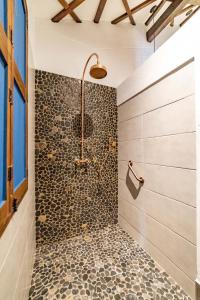 y baño con ducha y pared de piedra. en Casa Jacaranda Hotel Boutique en Jericó